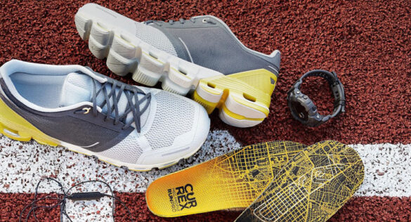 Laufschuh-Einlagen, Laufschuhe und Sportuhr auf einer Tartanbahn